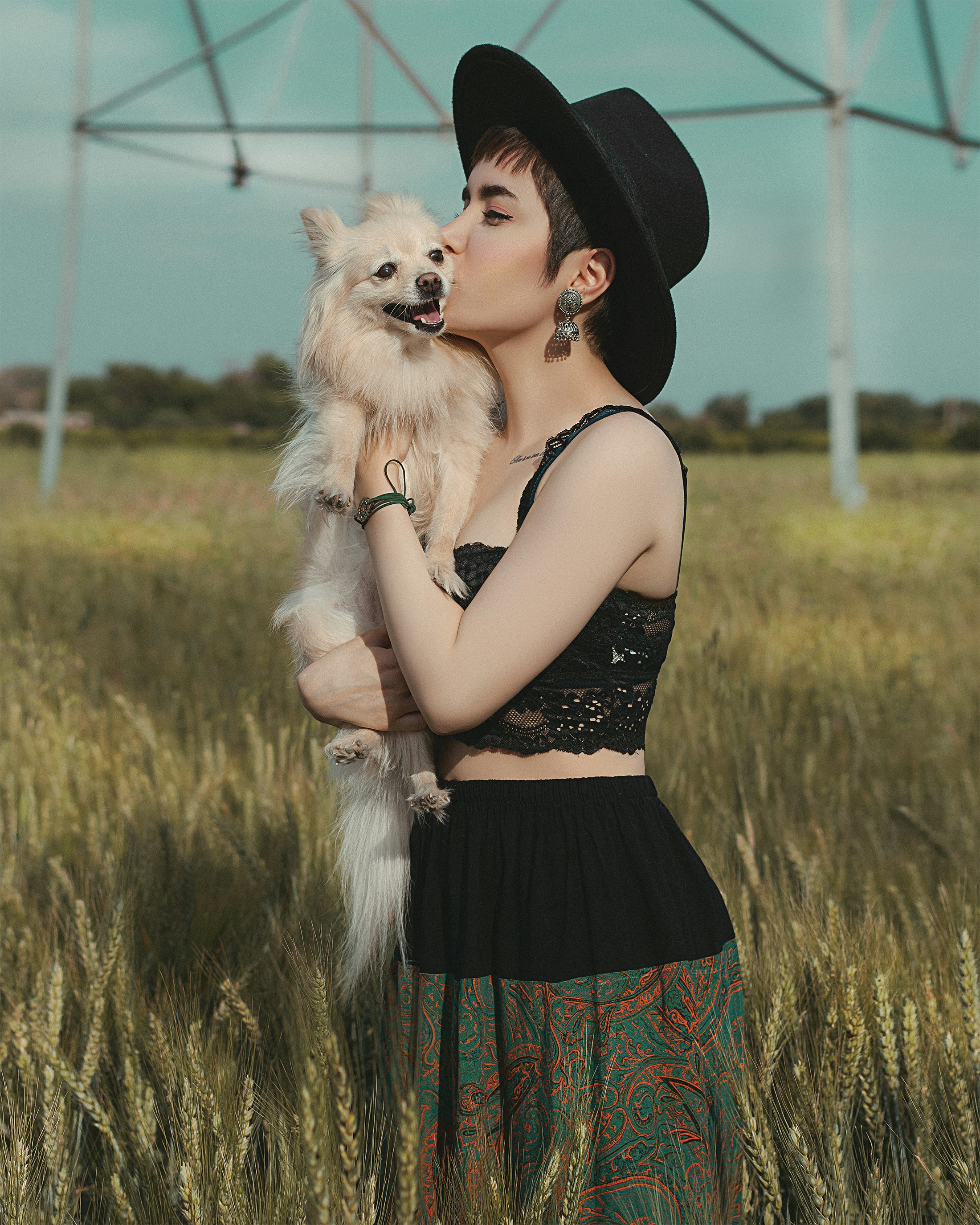 woman in black and red floral dress holding white long coated small dog